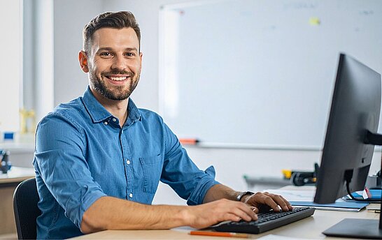 Ein Mann sitzt an einem Schreibtisch vor dem Computer
